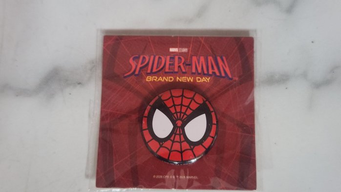 限量電影《蜘蛛人：重生日》（Spider-Man: Brand New Day）的上映紀念徽章，附帶紅色的蜘蛛人標誌包裝卡紙